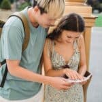 Content young Asian couple in casual wear traveling in new city and checking direction in paper map