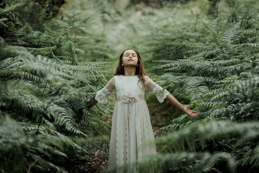 A Girl in a White Dress Standing in a Forest with Eyes Closed