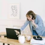 Woman Talking on the Phone and Looking at a Laptop