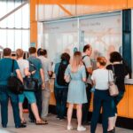 Back view of unrecognizable people in casual wear standing near ticket office in public place