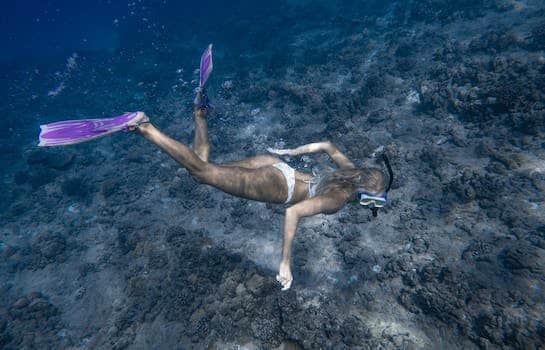 Anonymous lady swimming undersea near reef