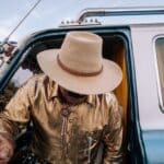 A man in a cowboy hat and gold jacket is in the back of a truck