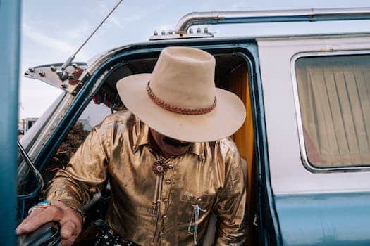 A man in a cowboy hat and gold jacket is in the back of a truck