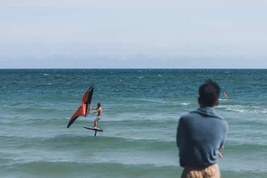 A man is standing in the ocean with a kite