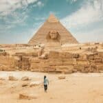 Back view of unrecognizable man walking towards ancient monument Great Sphinx of Giza
