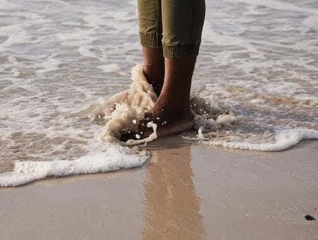 Crop black person standing on wet coast