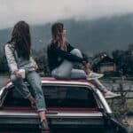 Two Women Sitting on Vehicle Roofs