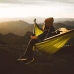 Unrecognizable woman sitting in hammock above mountains