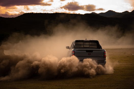 A truck driving through the dust on a field